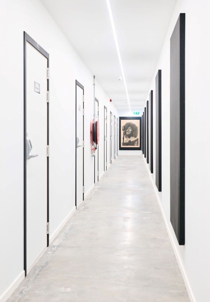 Music studio corridor with white walls and doors and black acoustic panels. | © Plug The Jack