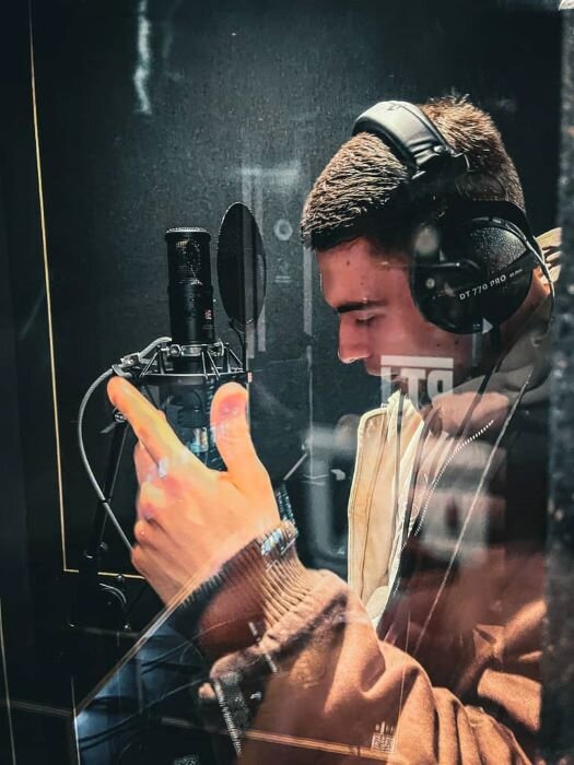 Singer in recording studio's vocal booth with microphone and headphones. | © Plug The Jack