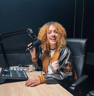 Female podcaster in front of a Rodecaster Pro console in a podcast studio. | © Plug The Jack