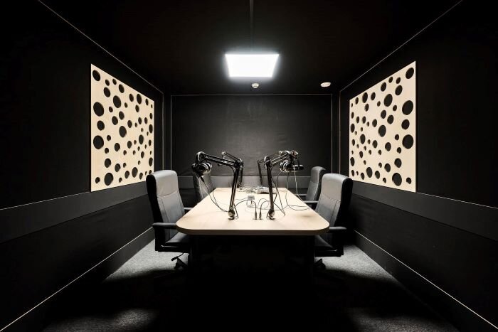 Podcast studio equipped with leather chairs, microphones, and complete setup. | © Plug The Jack