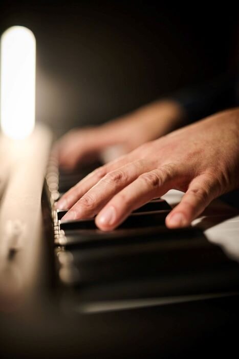 Mains sur un piano de scène dans un local de répétition. | © Plug The Jack