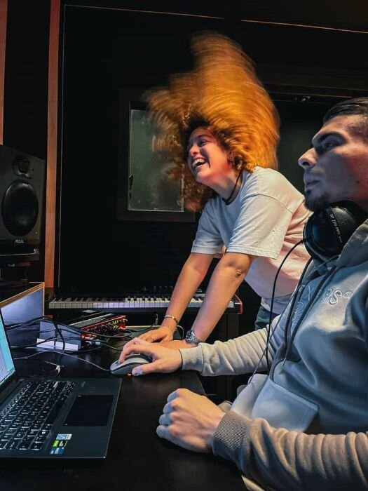 © Plug The Jack Geluidstechnicus voor een scherm met luidsprekers in een opnamestudio, zangcabine op de achtergrond. | © Plug The Jack