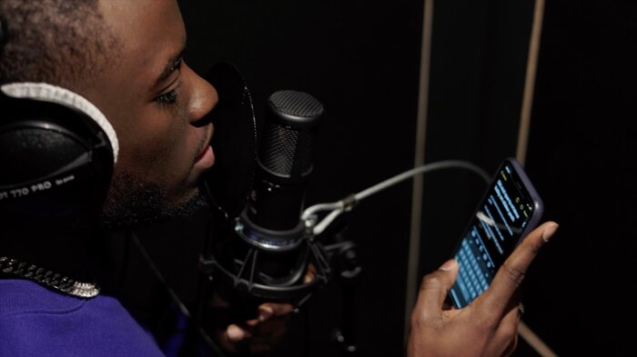 Chanteur au micro en cabine, texte sur son téléphone